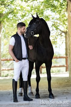 a man standing next to a black horse