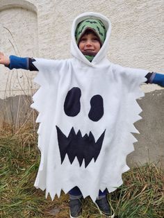 a young boy dressed up as a ghost with his arms out in front of him