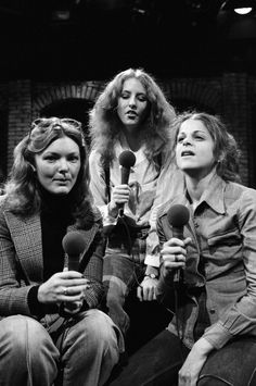 three women sitting next to each other in front of a microphone