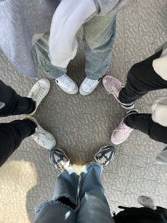 four people are standing in a circle with their feet up and one person is wearing white shoes