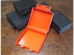 an orange box sitting on top of a wooden table next to other black boxes and cases