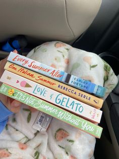 a baby in a car seat holding four books on top of it's head