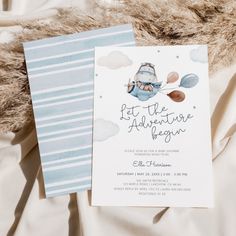 two blue and white baby shower items on top of a bed next to each other