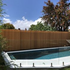 an empty swimming pool in front of a wooden fence