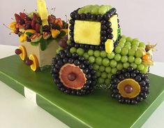 a truck made out of fruit sitting on top of a green table next to a potted plant