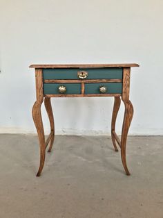 a small wooden table with two drawers on one side and gold knobs on the other