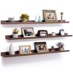 three wooden shelves with pictures and other items on them, one shelf has an alarm clock