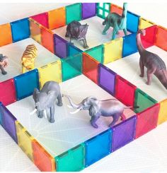 several toy animals are placed in an open area made out of colored plastic cubes