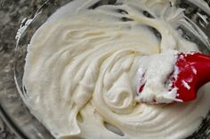 a red spatula in a glass bowl filled with whipped cream