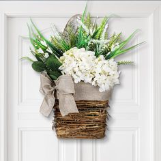 a basket filled with white flowers on top of a door