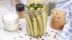 a jar filled with cucumbers sitting on top of a table next to other jars