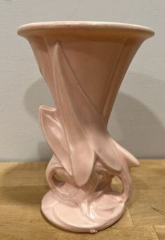 a pink vase sitting on top of a wooden table