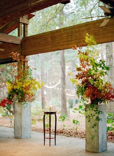 two tall vases with flowers in them sitting on the ground