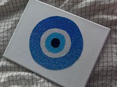 a blue and white painting with an eye on it's side sitting on a bed