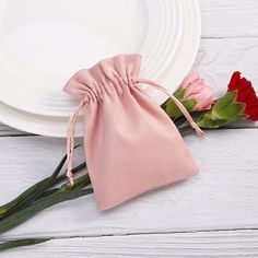 two roses in a pink pouch next to a white plate