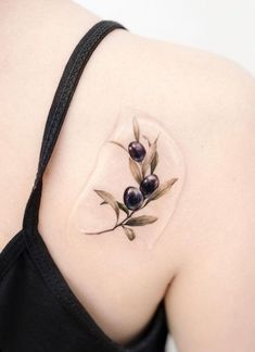 the back of a woman's shoulder with an olive branch tattoo design on it