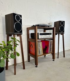 two speakers and a record player are on the floor next to each other in front of a white wall