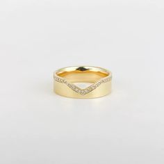 a yellow gold wedding band with white diamonds on the sides and a curved design in the middle