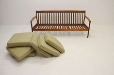 a wooden bench with four cushions sitting next to it