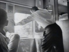 black and white photograph of two men looking out the window at another man standing next to him