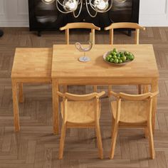 a wooden table with chairs and a bowl of fruit on it