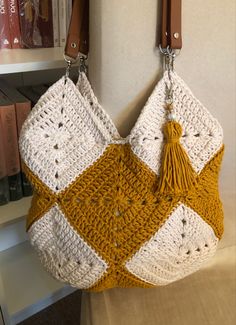 a crocheted purse hanging on the wall in front of a bookshelf