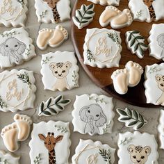 cookies decorated with baby animals and leaves are on a table next to a wooden platter