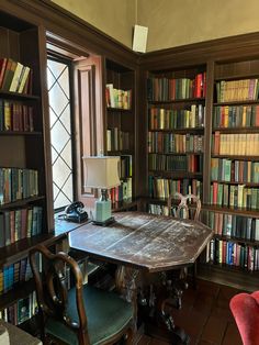 a room filled with lots of books next to a table covered in red velvet chairs