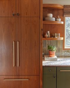 a kitchen with wooden cabinets and green cupboards next to a white counter top in front of a window