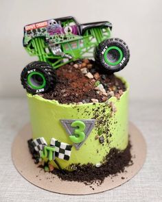 a monster truck birthday cake with dirt on the bottom and green icing around it