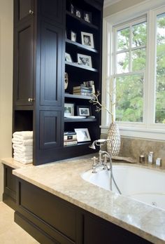 a bath room with a sink and a book shelf next to a window on the wall