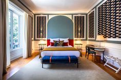 a bed room with a neatly made bed next to a desk and two lamps on either side of the bed