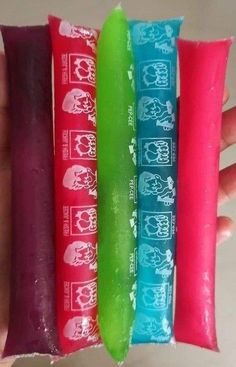 three different colored toothbrushes are in the hand