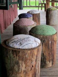 four wooden stools sitting on top of a wooden deck next to a tree stump