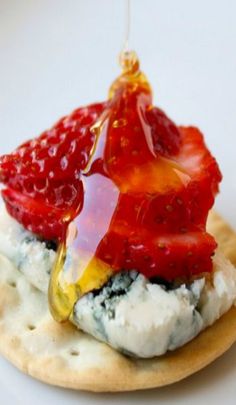 a strawberry jelly on top of crackers with cream cheese and strawberries being drizzled over them