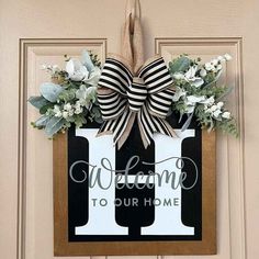 a welcome to our home door hanger with flowers and ribbon on the front door