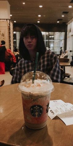 a woman sitting at a table with a starbucks drink