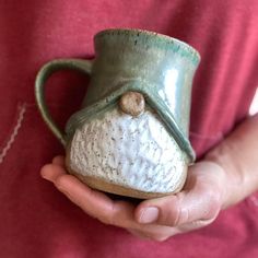 a person holding a ceramic mug in their hands