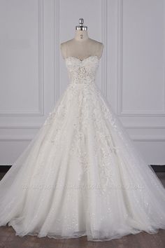 a white wedding dress on a mannequin stand in front of a white wall