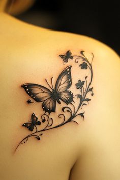 a butterfly tattoo on the back of a woman's left shoulder, with flowers and butterflies around it