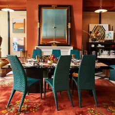 a dining room with orange walls and blue chairs around a black table surrounded by colorful rugs