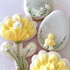 decorated cookies with yellow flowers and white frosting in the shape of eggs on a table