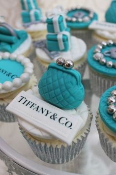 cupcakes decorated with blue and white icing on a glass plate that says tiffany & co