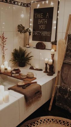 a bath room with candles and towels on the counter next to a mirror that says take a bath you dirty hippie