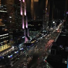 an aerial view of a city at night with cars and buildings in the foreground