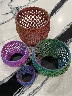 three different colored baskets sitting on top of a white counter next to black and silver lines