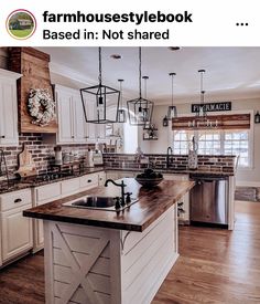 a kitchen with white cabinets and wooden counter tops, an island in the middle is surrounded by hanging lights