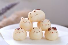 small white cat figurines sitting on top of a plate