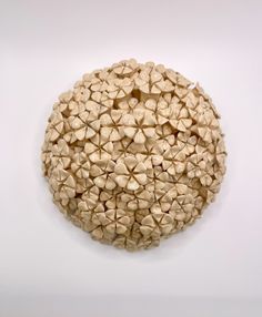 a circular object made out of small rocks on a white surface with no one around it