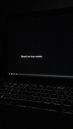 an open laptop computer sitting on top of a black table in the dark with text reading based on true events